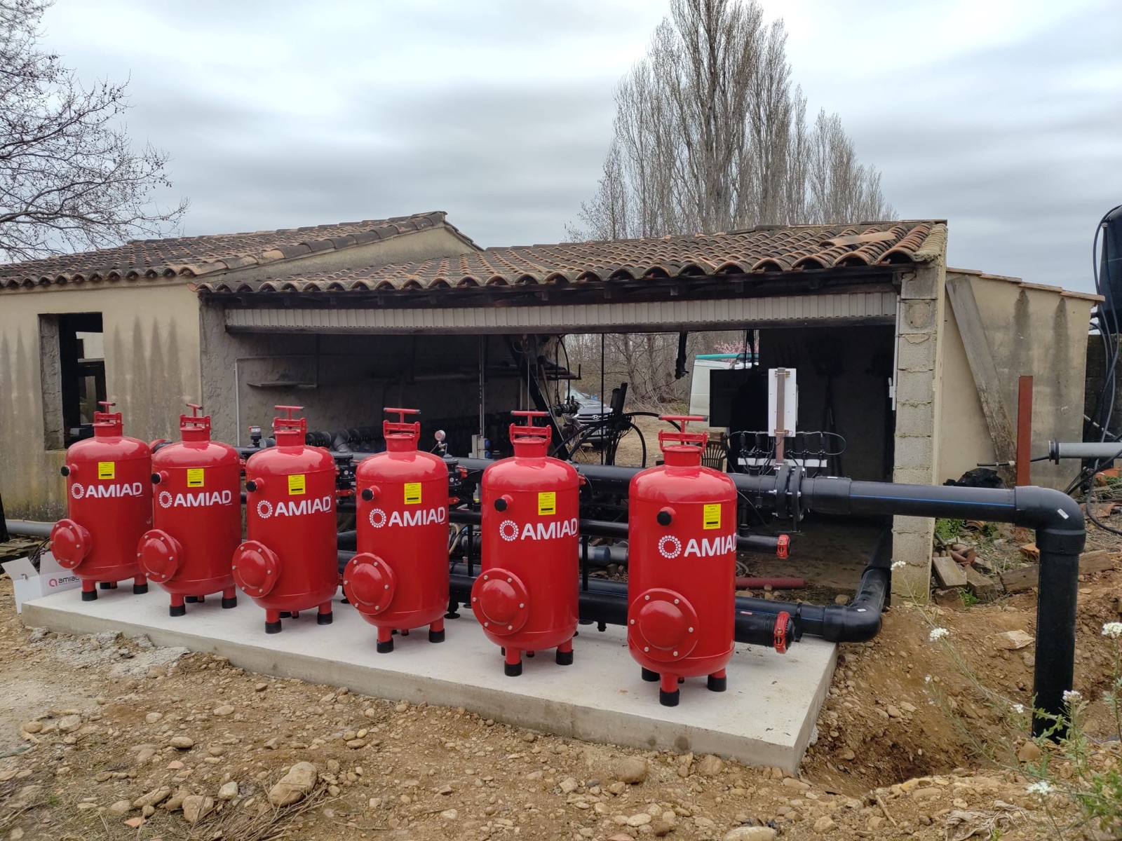 Station de filtration : batterie de filtres rouges sur dalle béton, sous abri — 2A AUTOMATISMES