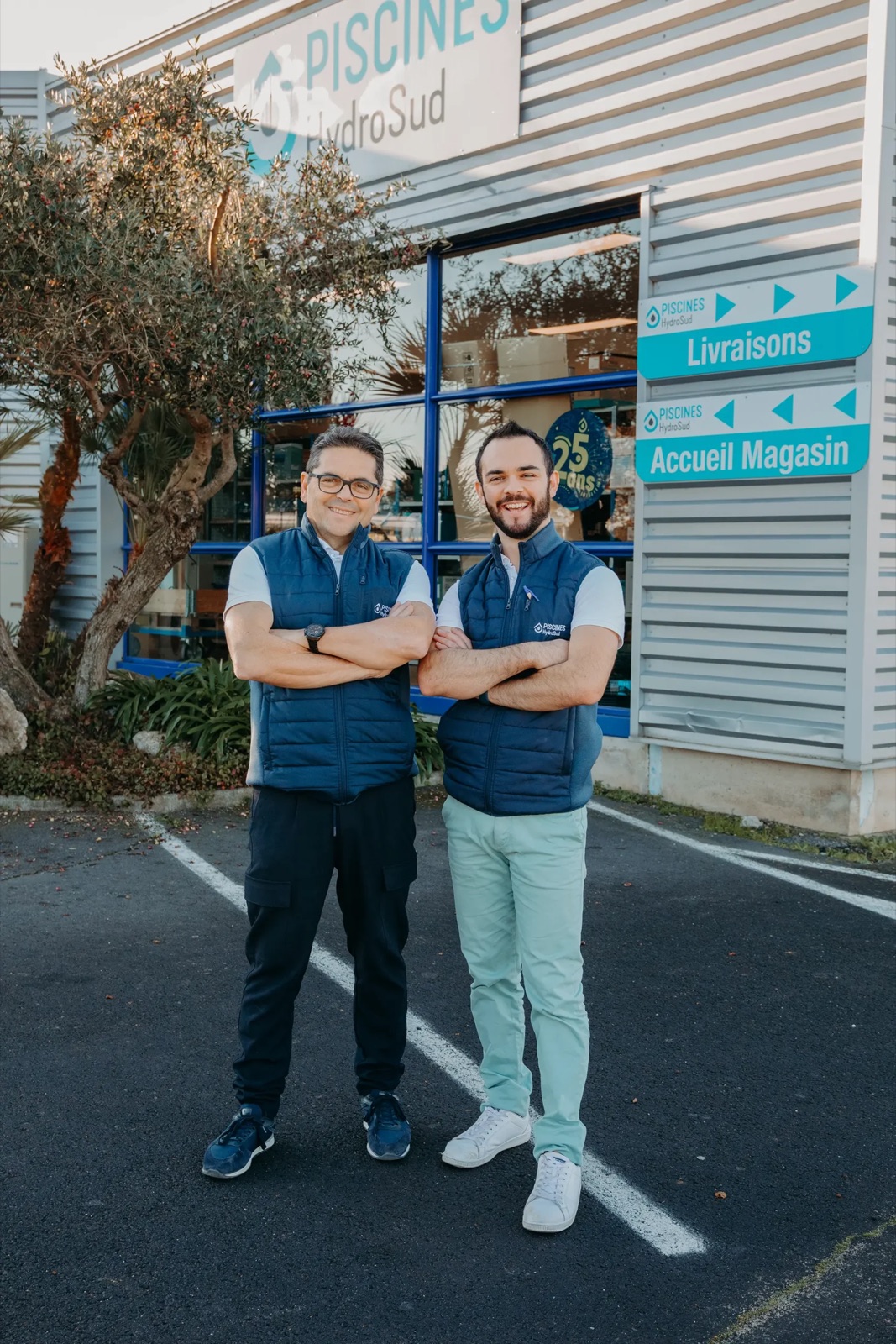Deux hommes devant l'entrée du magasin, panneaux Livraisons et Accueil magasin, enseigne Piscines HydroSud visible — ALLINGRI