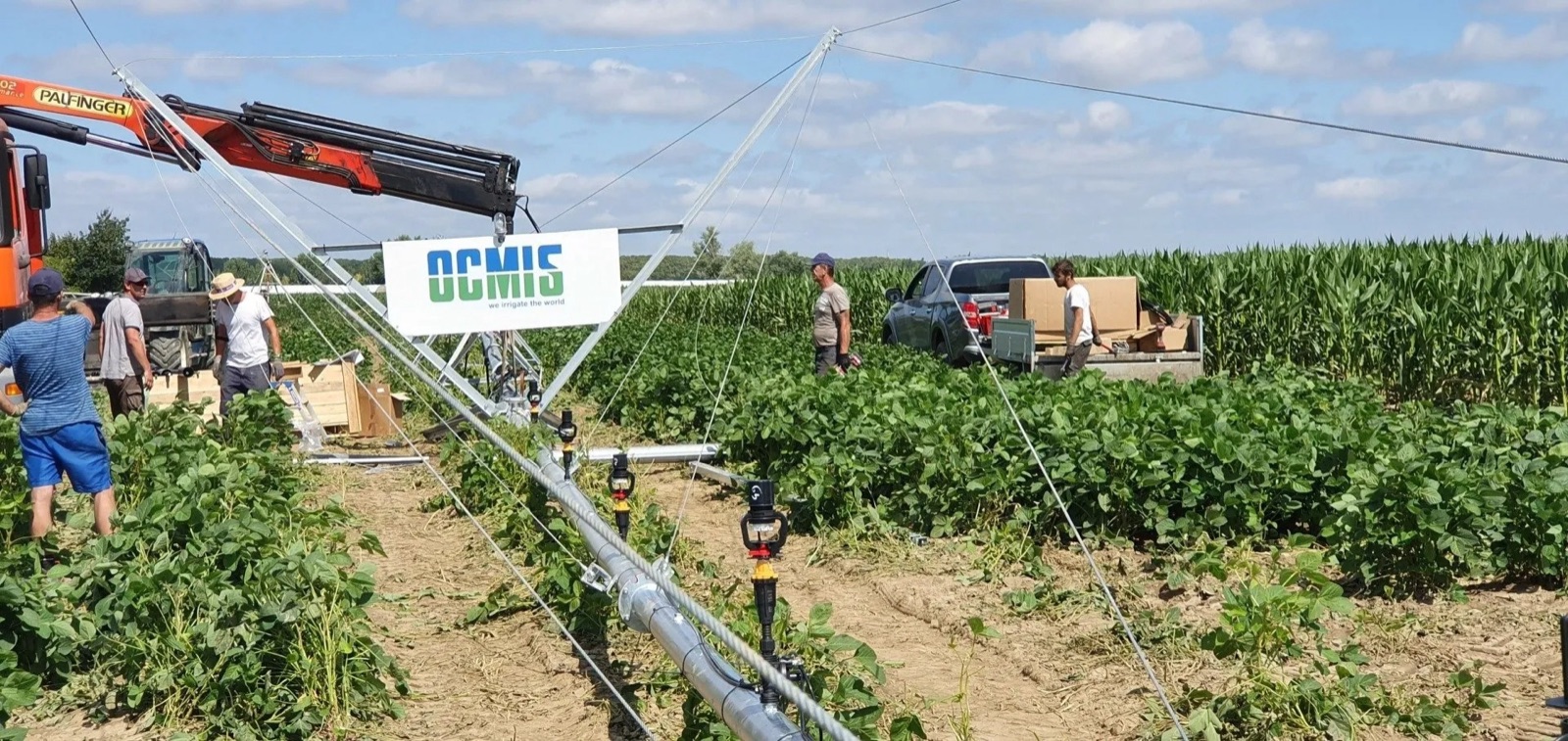 Chantier de montage d'une rampe ou d'un pivot OCMIS dans un champ de maïs, avec camion-grue — CG IRRIGATION