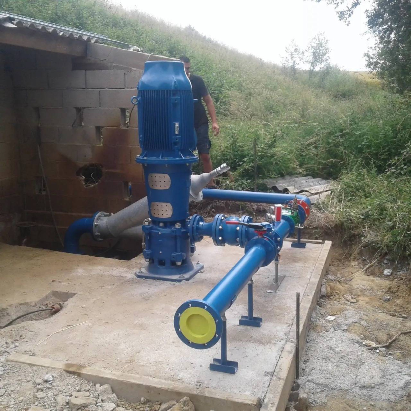 Station de pompage : pompe verticale bleue et conduite de refoulement sur dalle béton — CG IRRIGATION