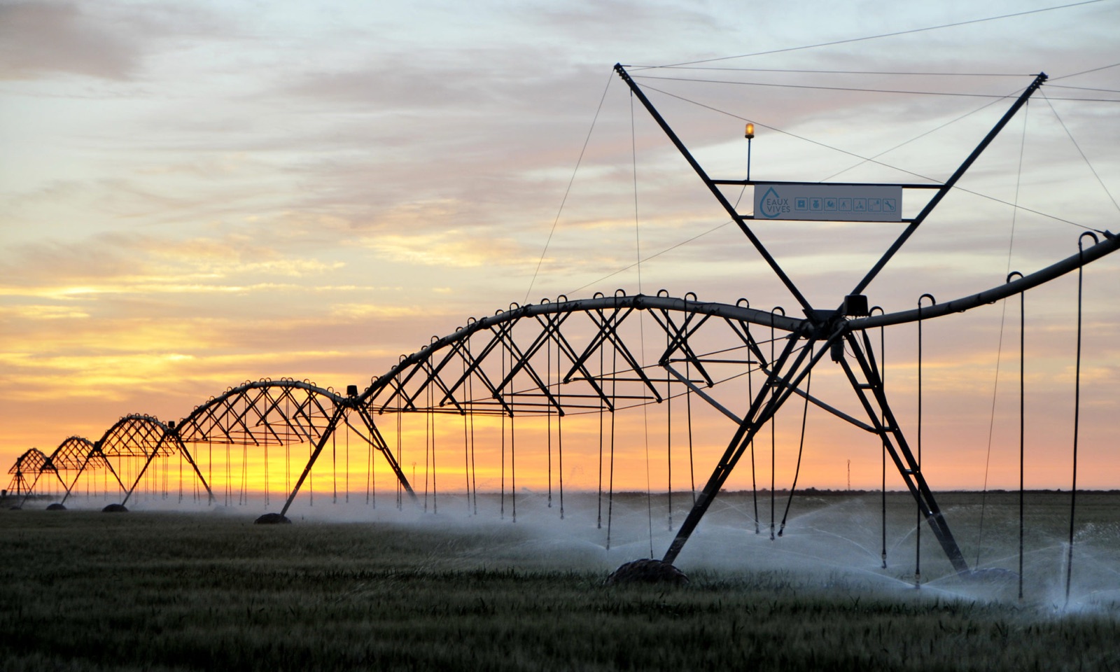 Rampe d'irrigation en fonctionnement au coucher du soleil — EAUX VIVES